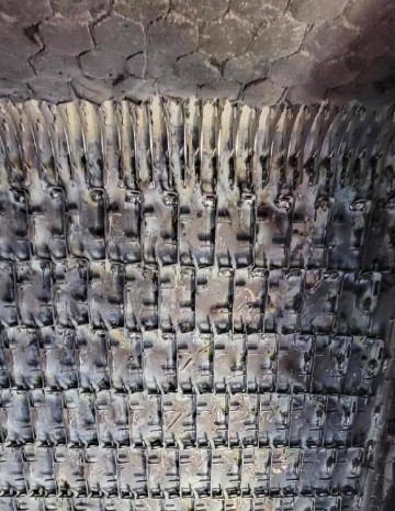 Close-up view of the underside of a tank’s metal tracks, showing multiple connected track links with visible wear and dirt.